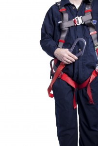 worker wearing blue coveralls and a fall protection harness and lanyard for work at heights